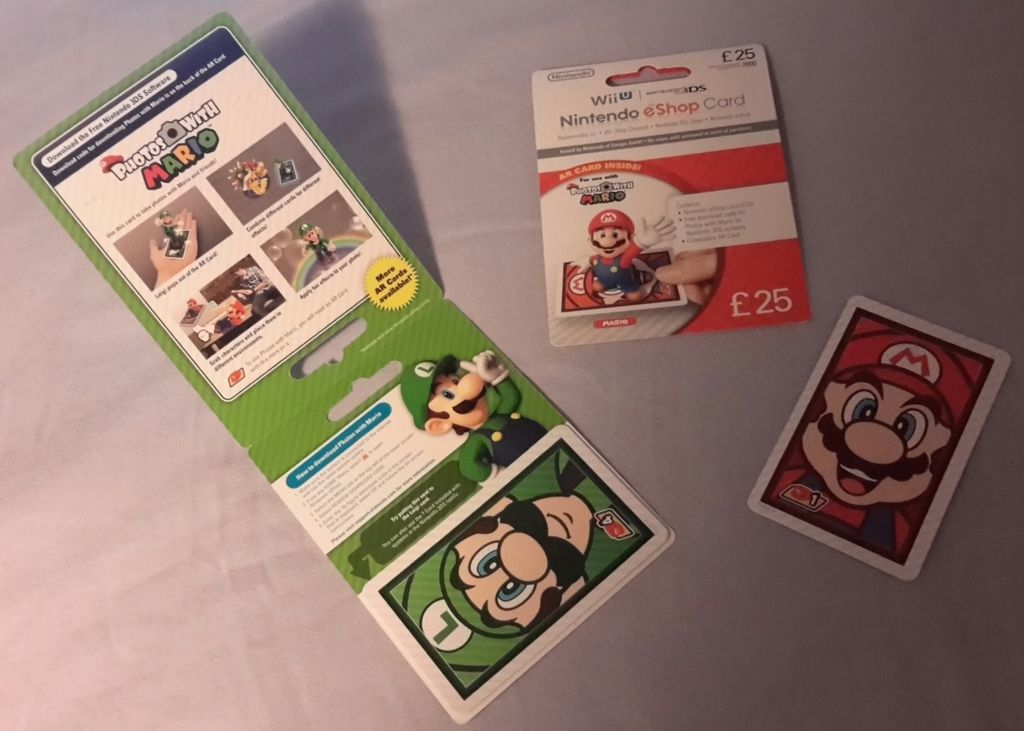 This is a photograph of a UK eShop card, £20 denomination, that includes the Photos with Mario AR Card printed on the eShop card. It also makes reference to the app itself.